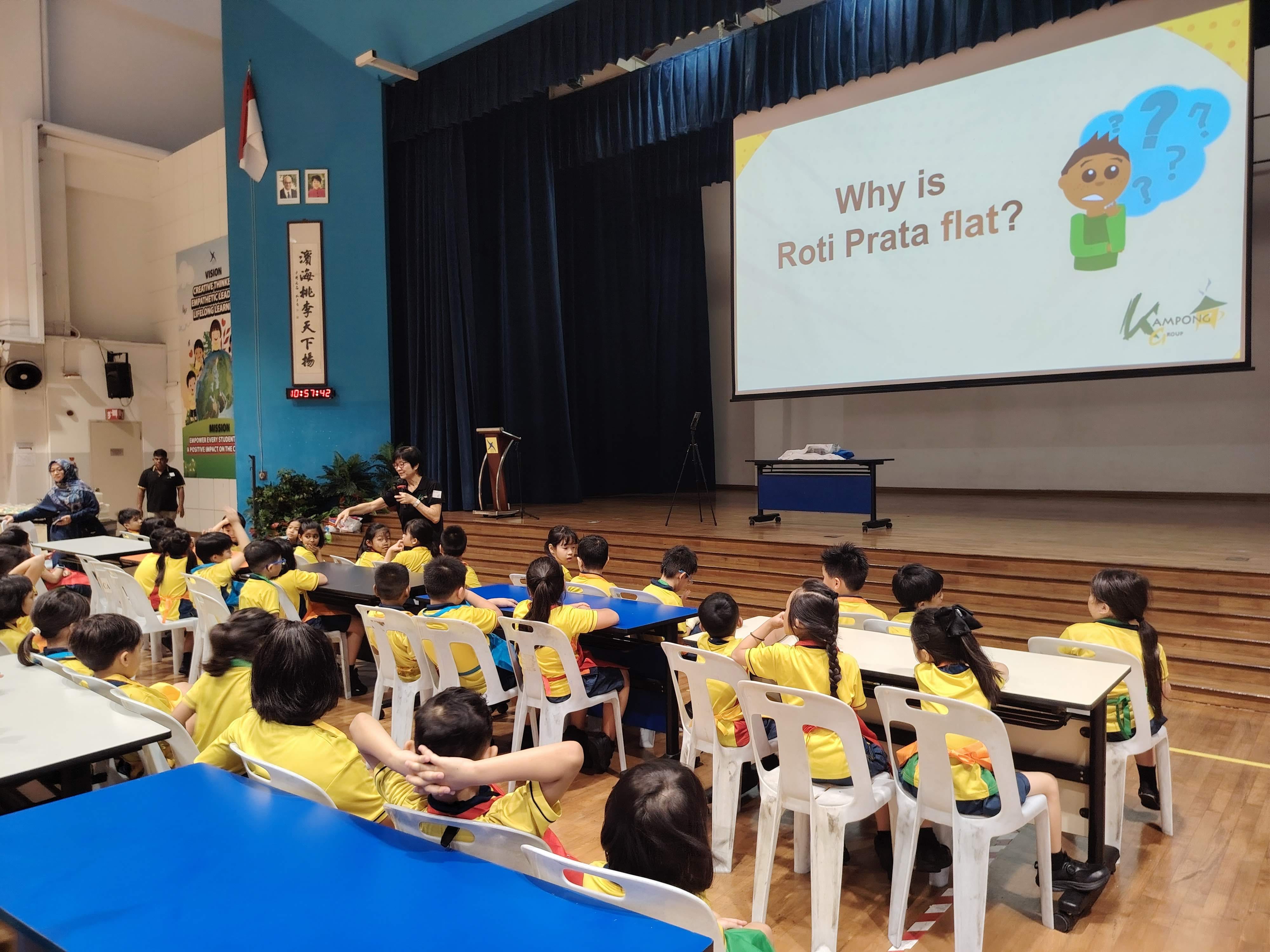 A presentation slide showing "Why is roti prata flat?" as the facilitator in front of the P2 students asked the same question.